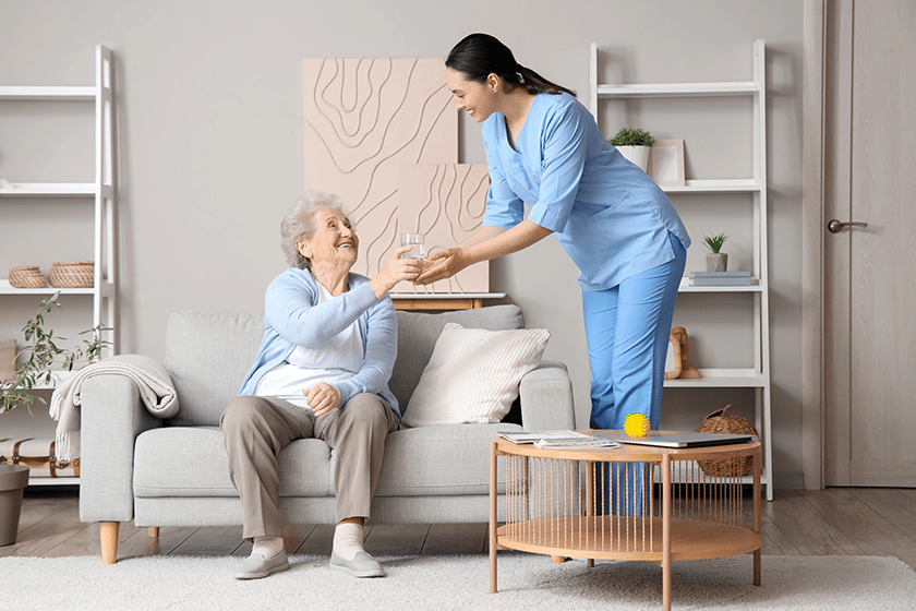 Senior woman taking glass of water from physical therapist