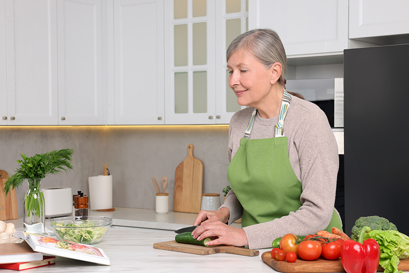 senior-woman-cooking-recipe-book-kitchen